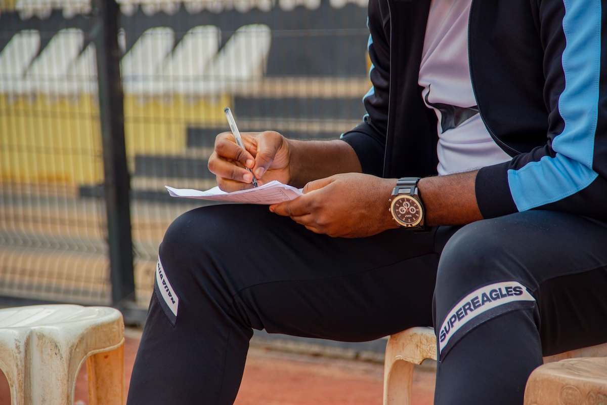 A coach manually writing down session notes and schedules on paper