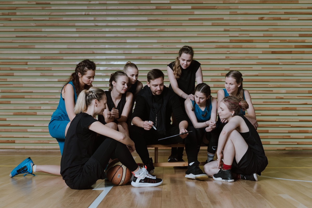 A coach going over a session plan with a group of young athletes